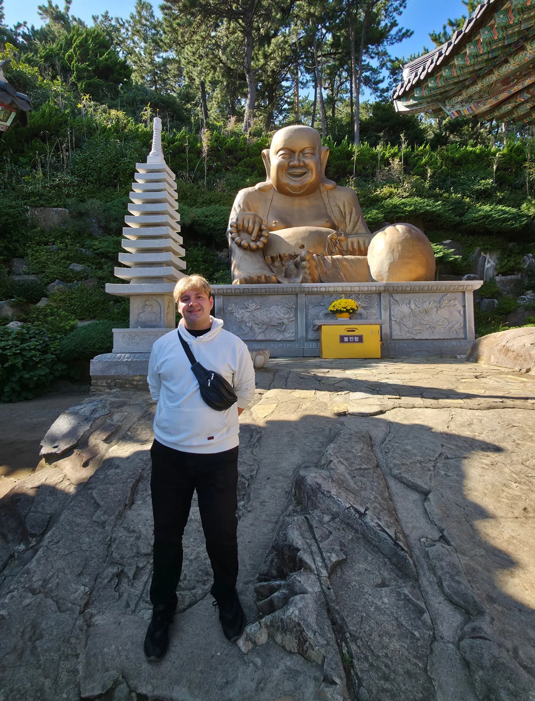 Viajero de Korea Tour junto al Buda dorado de la panza del templo Haedong Yonggungsa, en Busan, Corea del Sur
