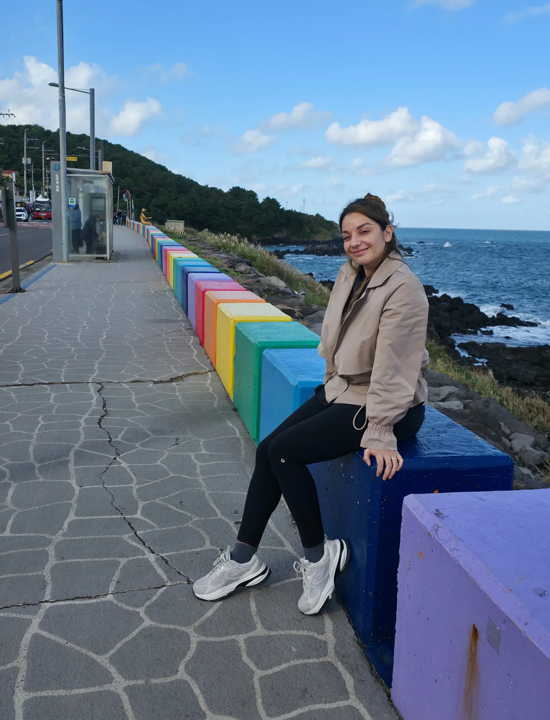 Viajera de Korea Tour sentada en los bloques de colores de la ruta costera del arcoíris, en Dodu, isla de Jeju