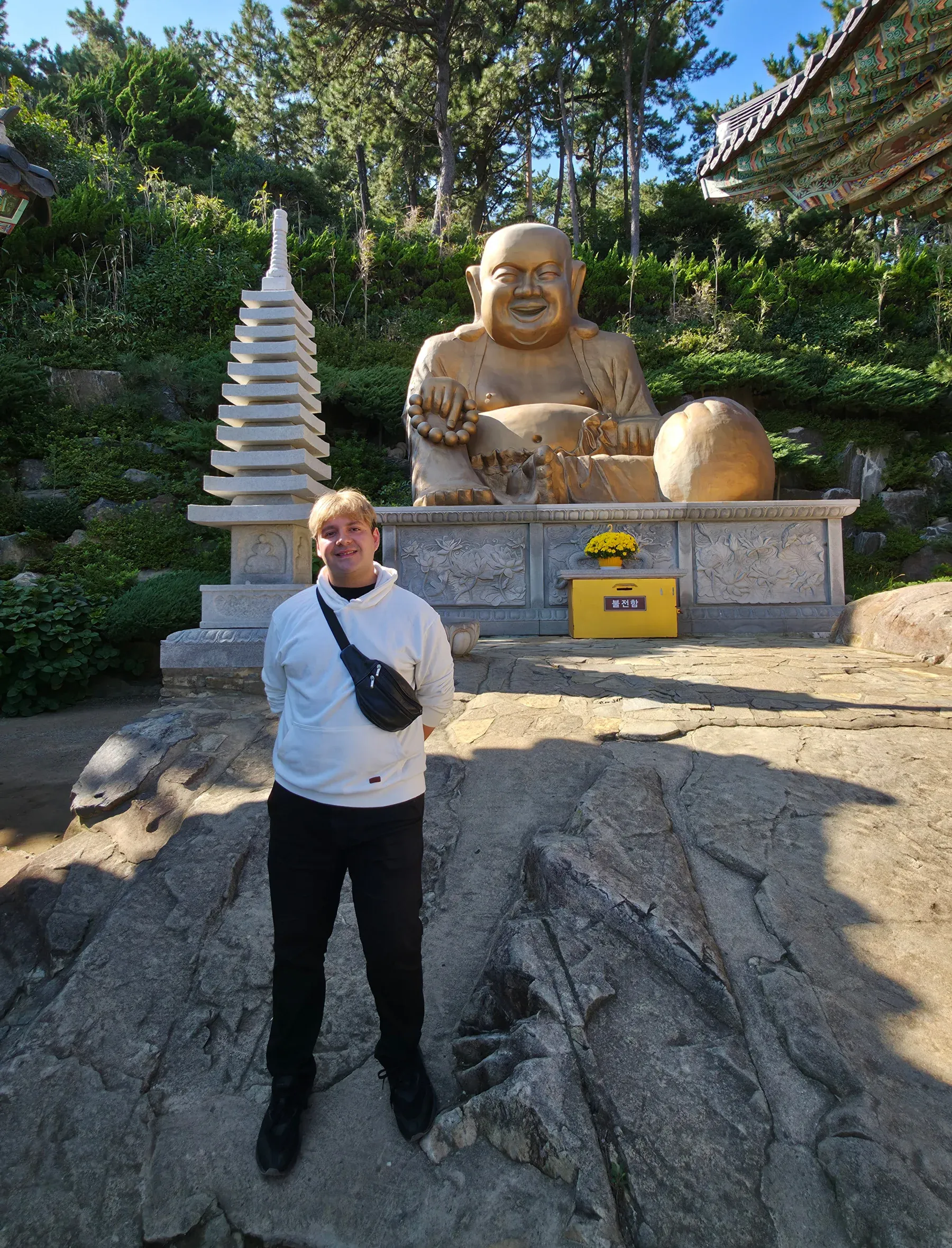 Viajero de Korea Tour junto al Buda dorado de la panza del templo Haedong Yonggungsa, en Busan, Corea del Sur