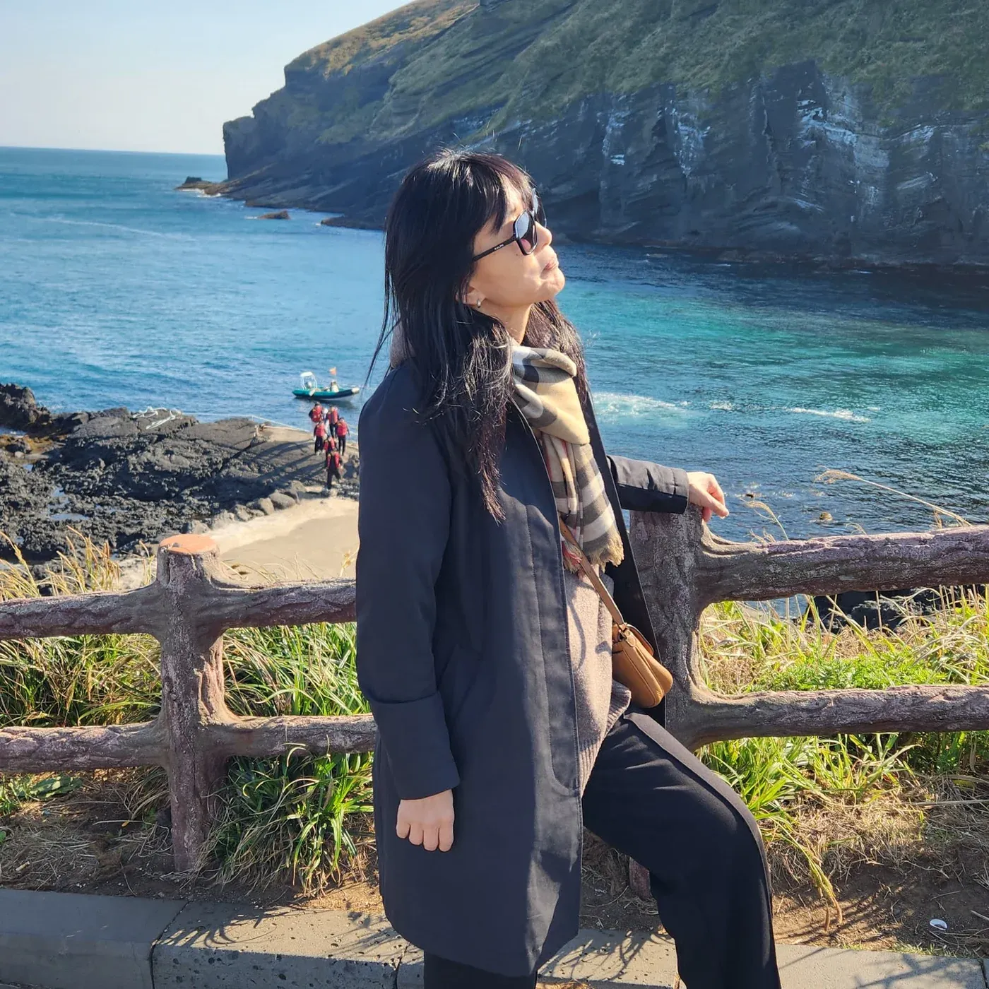 Viajera de Korea Tour en el cabo de Seopjikoji, isla de Jeju, con los acantilados volcánicos y el mar turquesa de fondo